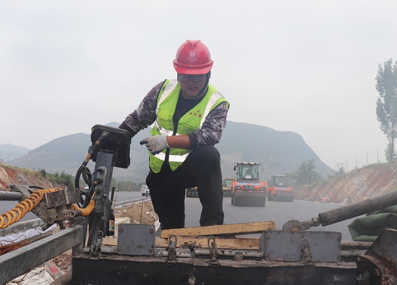 4、油層施工隊(duì)長朱紹濤根據(jù)現(xiàn)場(chǎng)實(shí)際微調(diào)攤鋪機(jī)控制攤鋪質(zhì)量_副本